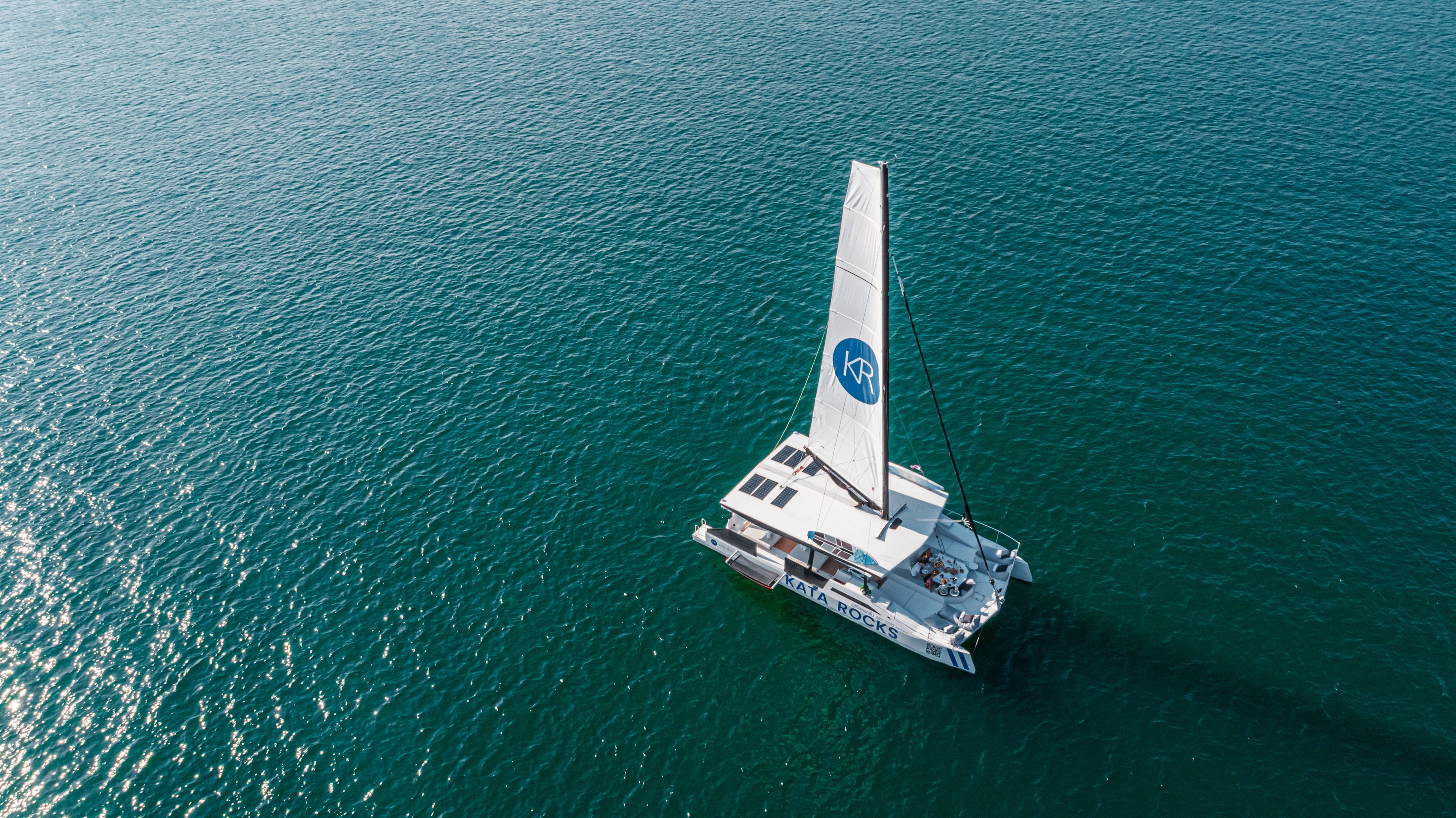 an aerial view of a luxury catamaran sailing in the Indian ocean. friends celebrating a special event with five star cuisine.