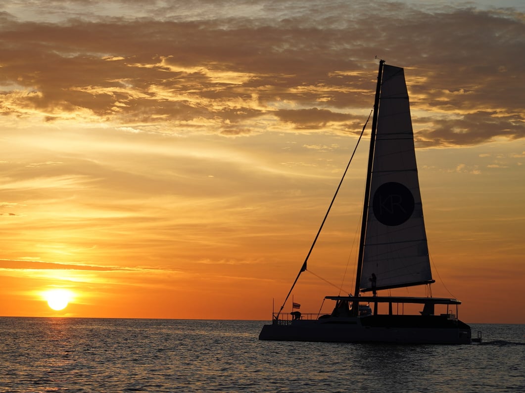 a catamaran sailing in the ocean at sunset