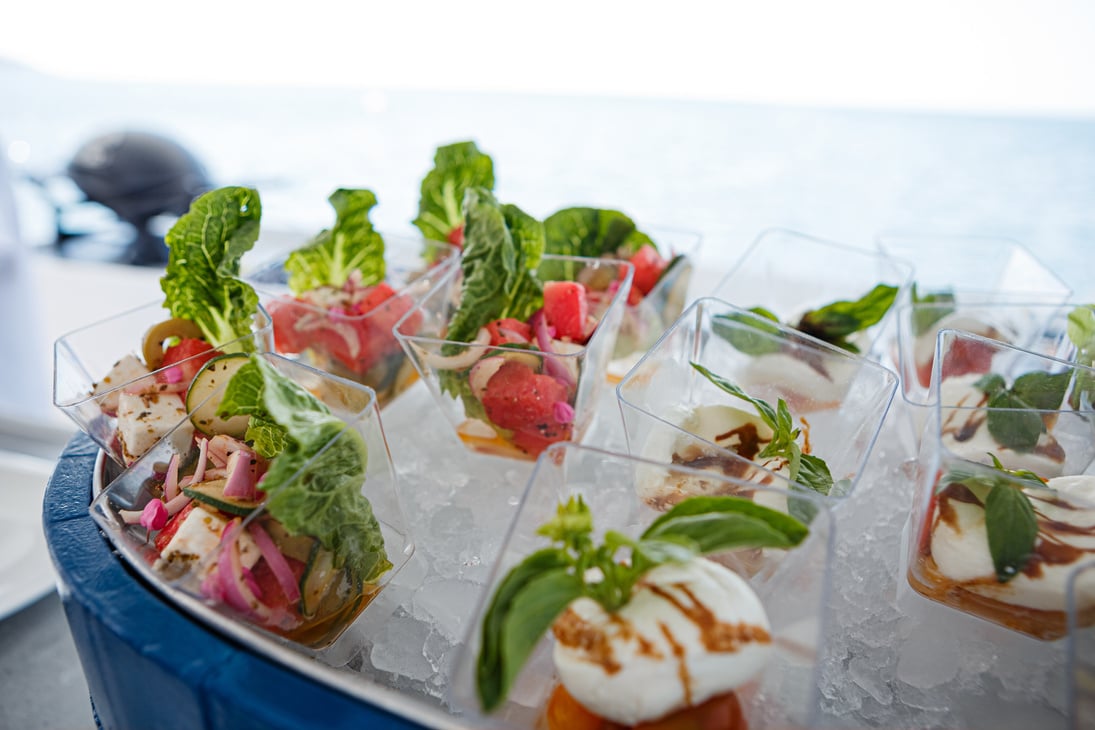 a tray of appetizers on a boat with the ocean in the background