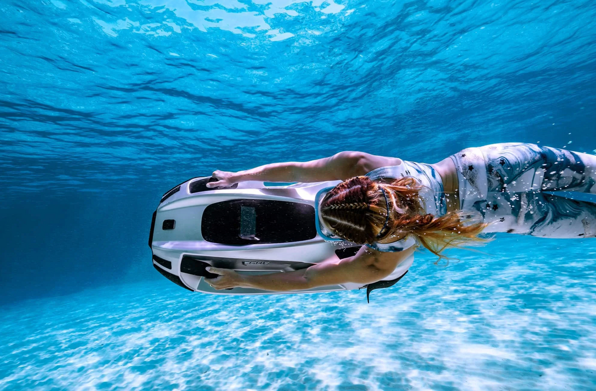 a person swimming in the ocean with an underwater vehicle iAqua water toy